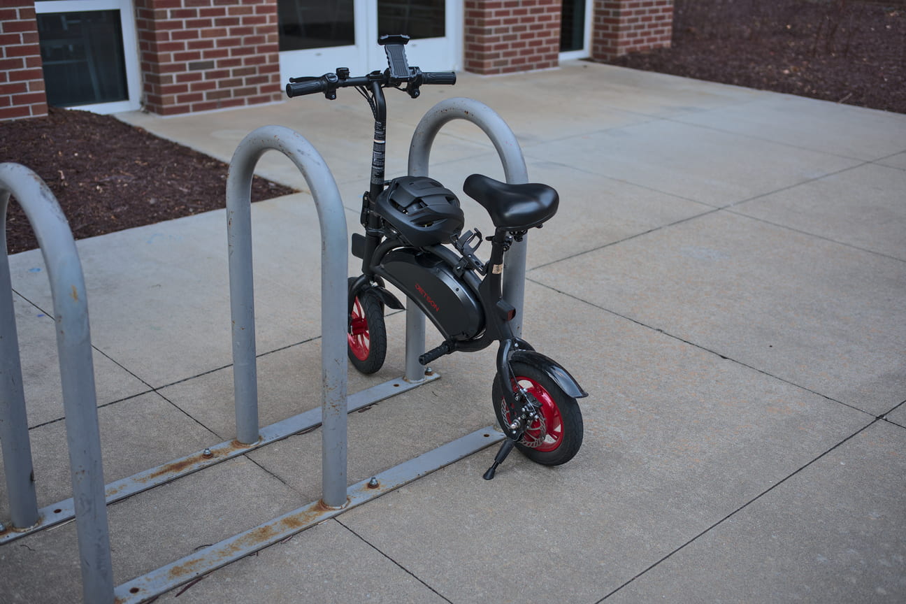 A black mini ebike locked to a rack.